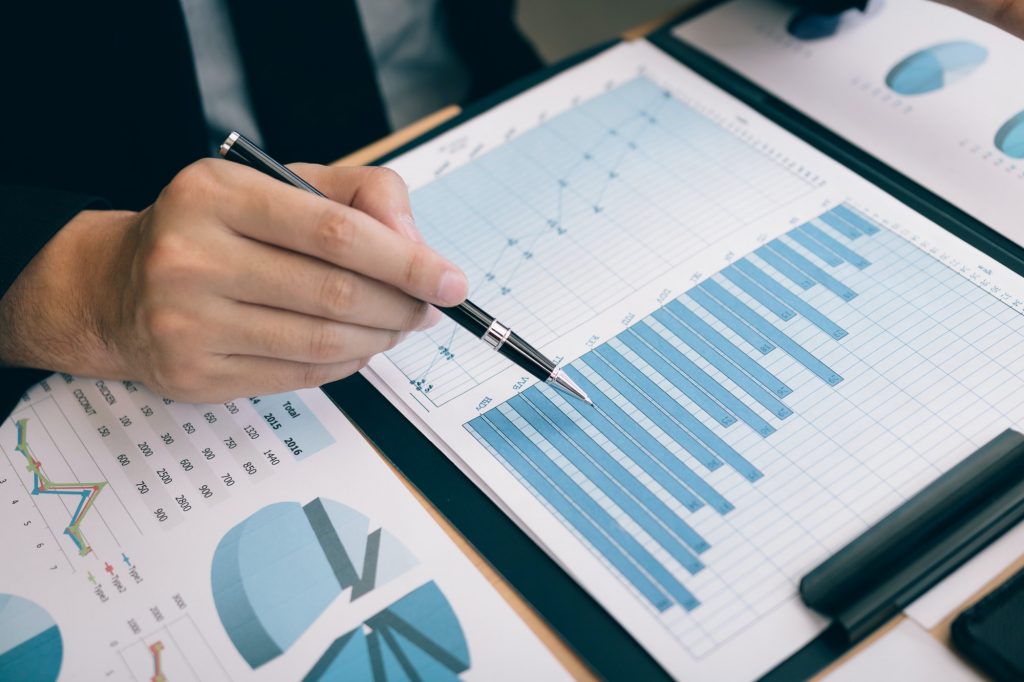 Businessmen are using the pen pointing to the cost and expense graph of the company.