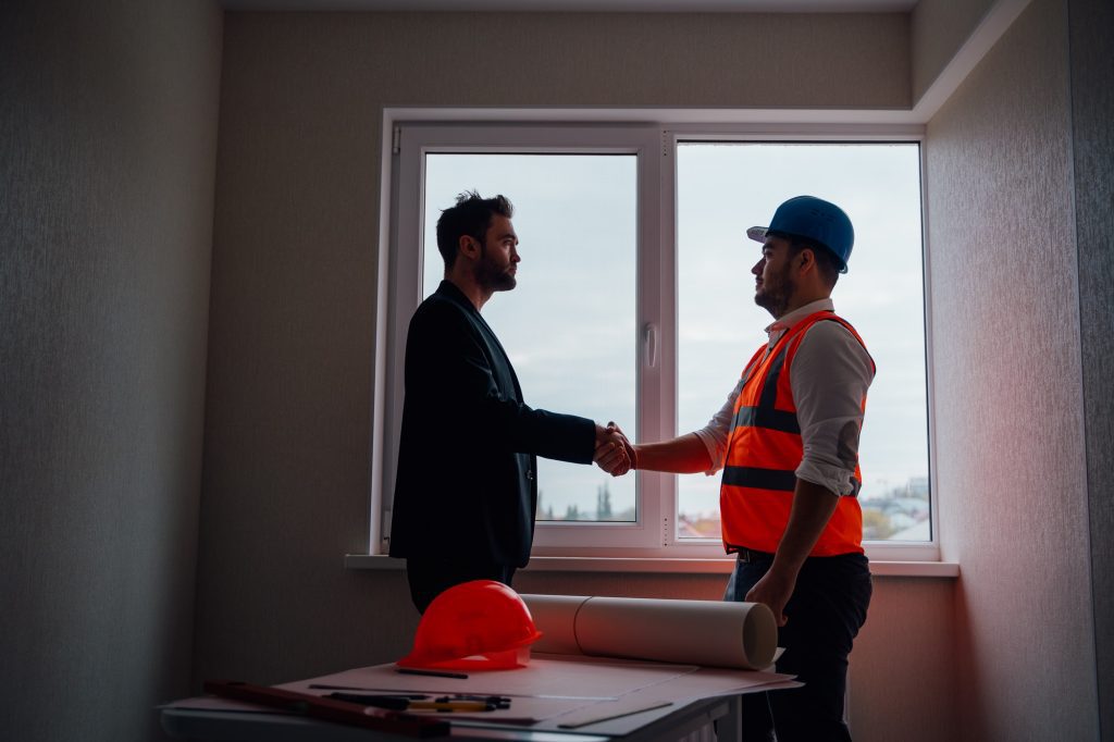 Side view of businessman and male contractor talking and shaking hands
